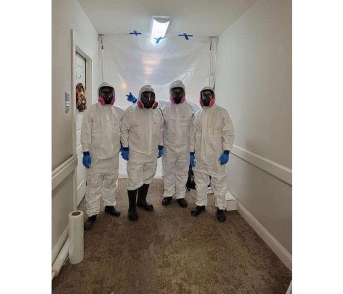 image of 4 people wearing white safety suits and masks