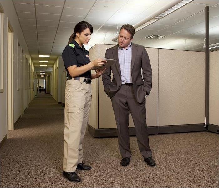 SERVPRO employee standing in office next to a person reviewing plans