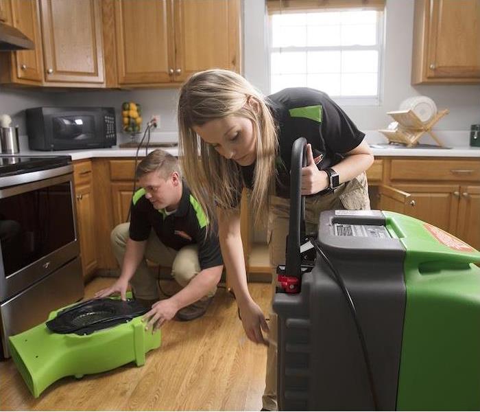 Two SERVPRO employees setting up air movers